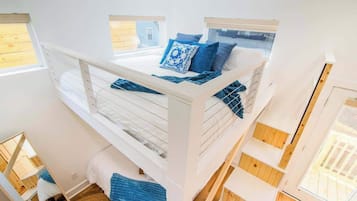 Habitación con literas de varios niveles, barandillas blancas y ropa de cama azul.