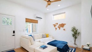 Una sala de estar moderna con un sofá, una mesa de centro, un mapa mundial en la pared y un ventilador de techo.