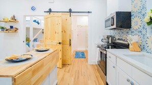Una cocina moderna con armarios de madera, un microondas y una puerta corredera que da a otra habitación.