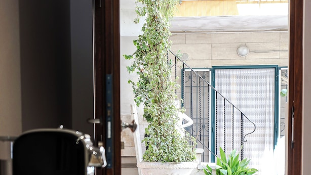 Ein modernes Interieur mit einer Kaffeemaschine, einer weißen Vase mit Pflanzen und Blick auf den Balkon.