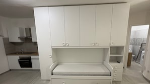 Ett litet rum med en inbyggd säng, ett minikök och ett badrum som syns genom en öppen dörr.