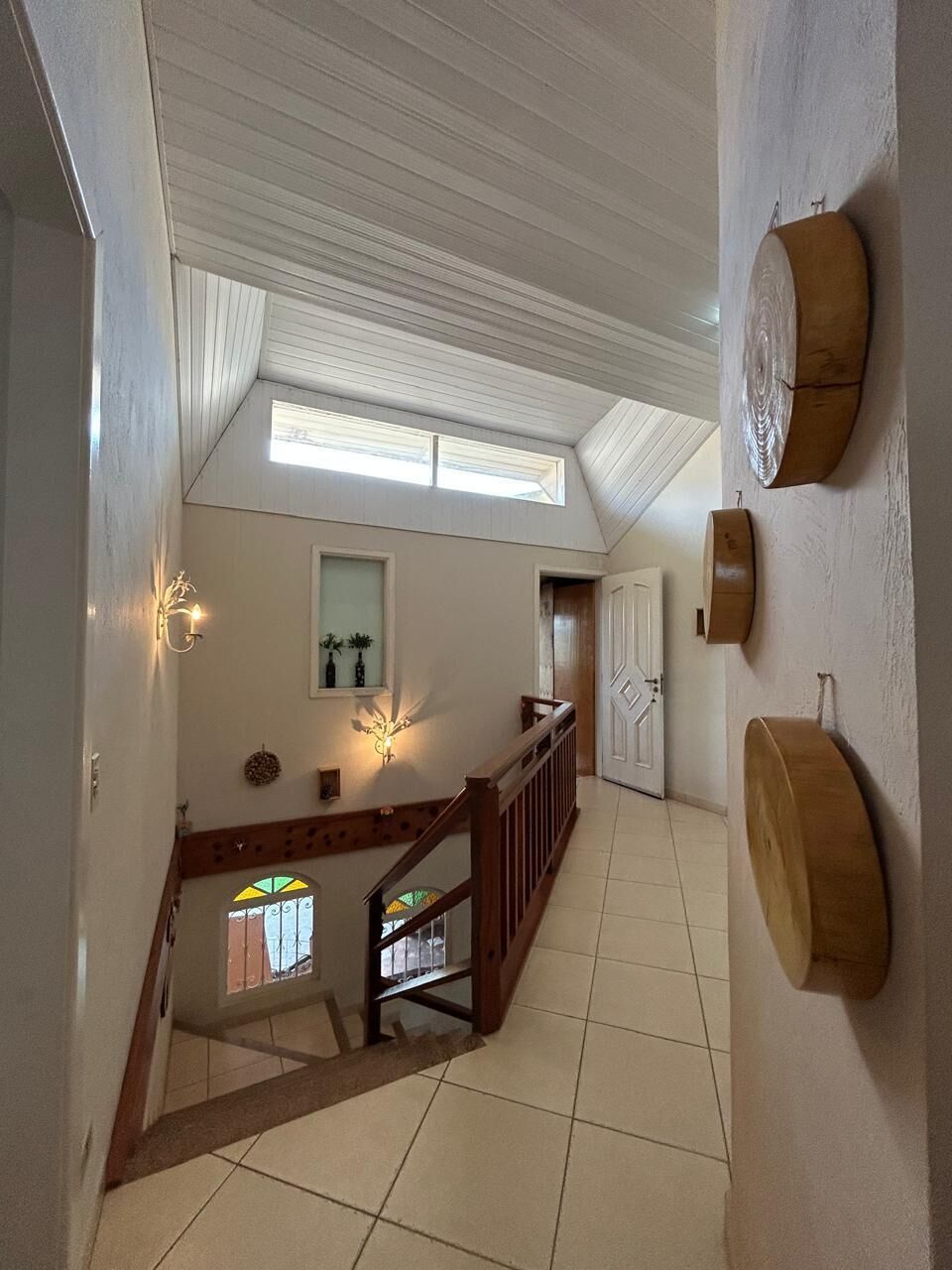 Eine Treppe führt zu einem Schlafzimmer auf dem Dachboden, das über eine Dachfenster, ein Holgitter und eine an der Wand befestigte Weinküfe verfügt.