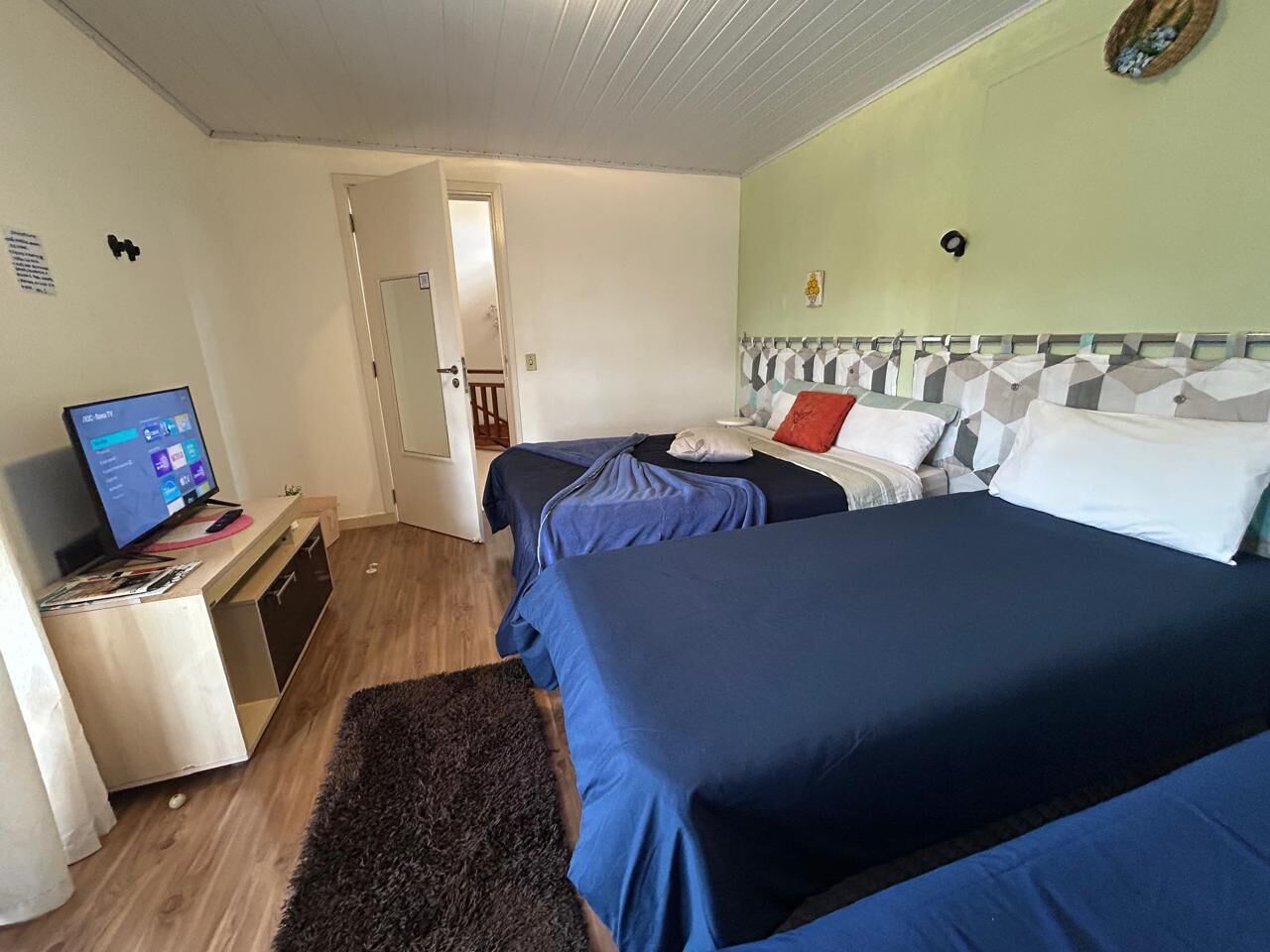 Una camera d'albergo con due letti, una scrivania con un computer e una porta che dà su un'altra stanza.