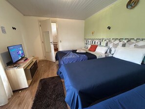 Een hotelkamer met twee bedden, een bureau met een computer, en een deur die naar een andere kamer leidt.