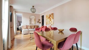 Un comedor con una mesa larga, sillas rosas y un cuenco decorativo.
