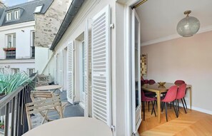 A modern apartment with a balcony, a dining area with red chairs, and a large window. - A RARE PRIVILEGE NEAR PALAIS GARNIER, GALERIE LAFAYETTE & MADELEINE - RUE D’ISLY (Paris)