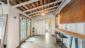 Un corridoio con soffitto in legno, un'area bar rustica e vista su un bagno.