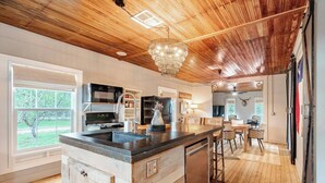 Una cucina moderna con soffitto in legno, un'isola centrale e zona pranzo con vista sull'esterno.