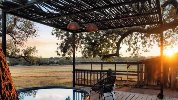 Un patio in legno con una pergola, una vasca idromassaggio e una sedia.