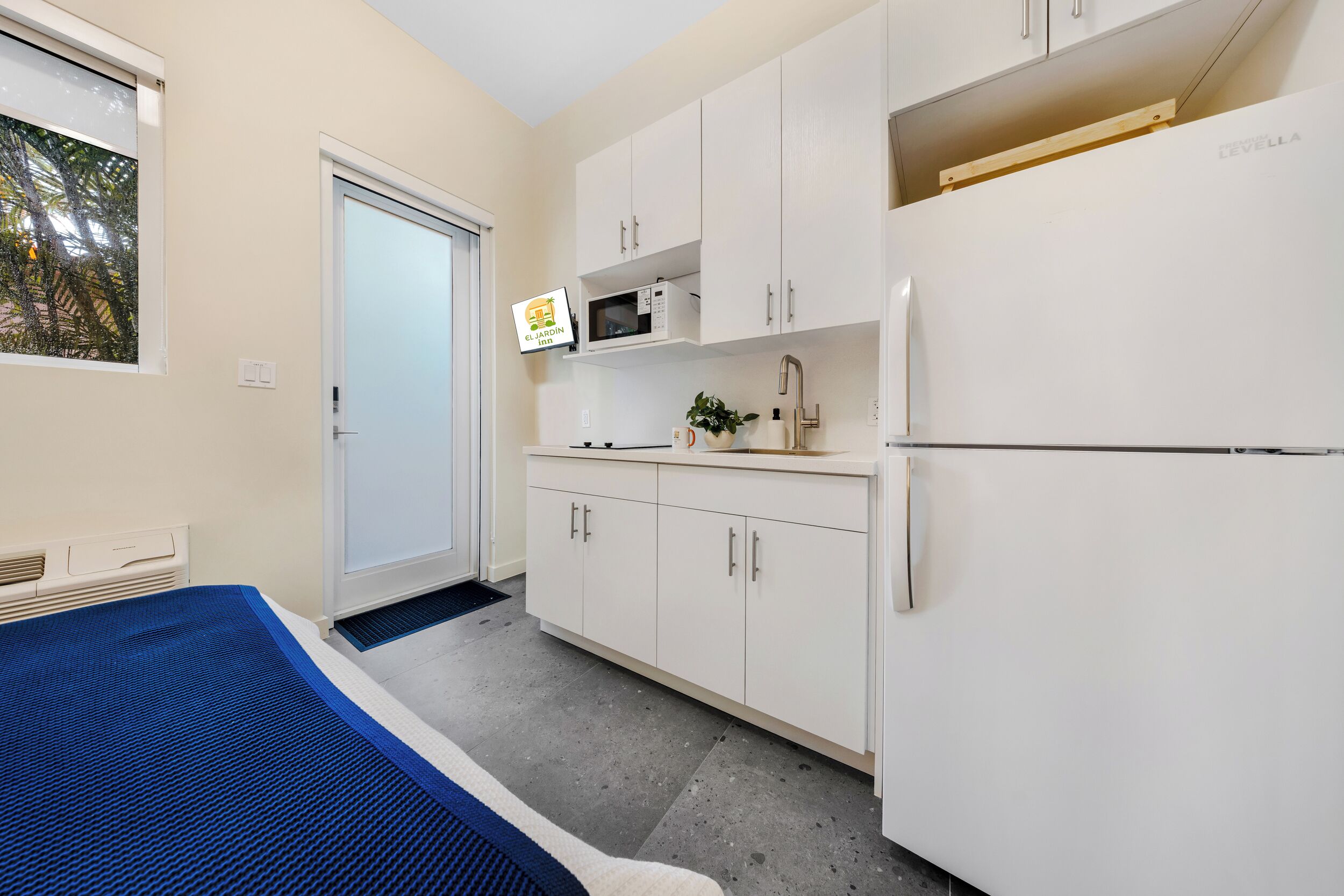 A compact kitchen with white cabinets, a microwave, and a refrigerator.