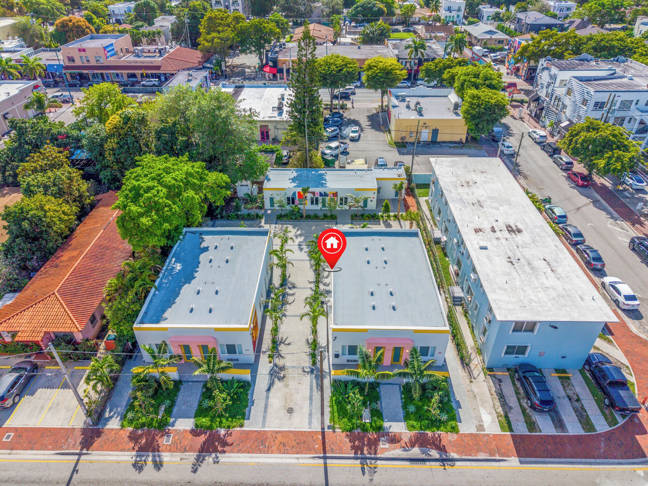An aerial view of a hotel with a central courtyard, parking area, and surrounding buildings.