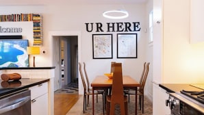 Une cuisine moderne avec une table à manger, des chaises et un panneau indiquant « VOUS ÊTES ICI » au-dessus.
