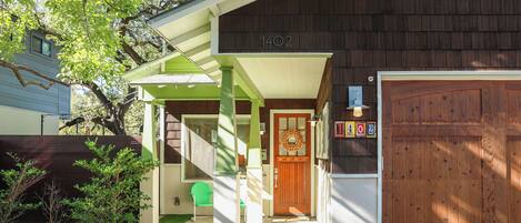 A house with a green porch, a wooden garage door, and a mailbox.