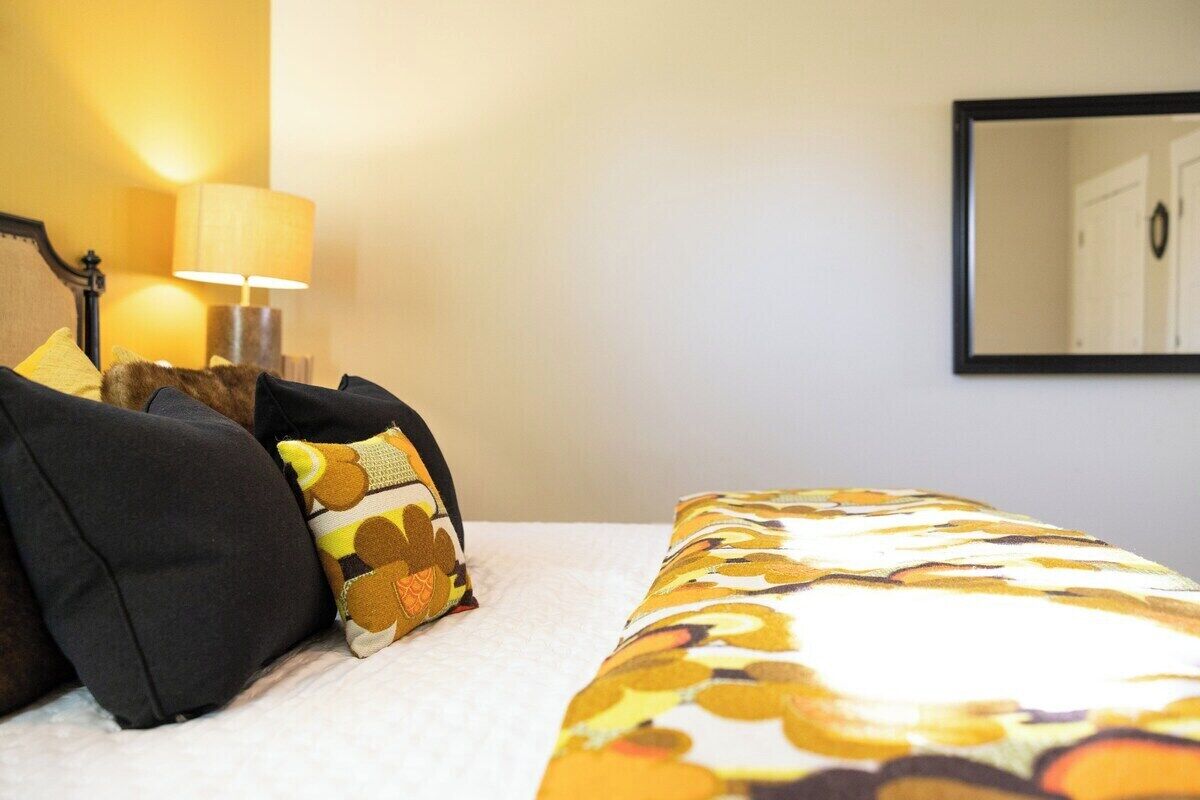 Une chambre d’hôtel avec un lit, des oreillers, une lampe et un miroir.