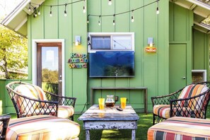 A green house with outdoor seating, a TV mounted on the wall, and a 'No Smoking' sign.
