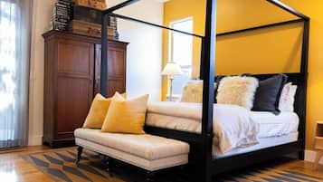 A four-poster bed with a bench, a wooden cabinet, and a patterned floor.