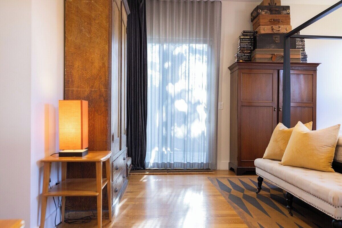 A room with a sofa, a cabinet, a lamp, and a window with curtains.