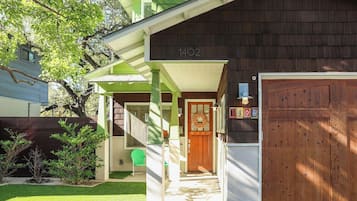 Une maison d’habitation avec un porche verdoyant, une porte de garage en bois et une boîte aux lettres.