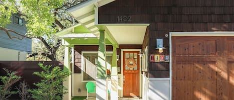 Una casa residencial con un porche verde, una puerta de garaje de madera y un buzón.