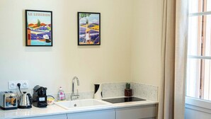 A compact kitchen with a sink, a small dining table with chairs, and two framed pictures on the wall. - Studio "Lavande" (Saint-Rémy-de-Provence)
