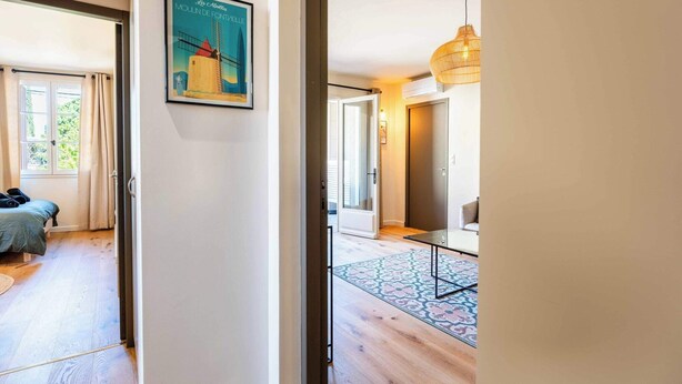 A hotel room with a bed, a door leading to another room, a patterned rug, and a framed picture on the wall. - Studio "Lavande" (Saint-Rémy-de-Provence)