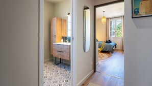 A hallway leading to a bedroom with a bed, a chair, and a window. - Studio "Lavande" (Saint-Rémy-de-Provence)