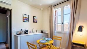 A compact kitchen with a dining area, featuring a sink, a coffee machine, and a small table with chairs. - Studio "Lavande" (Saint-Rémy-de-Provence)