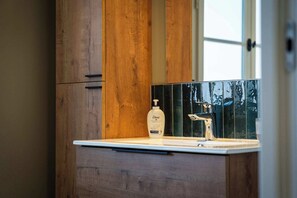 Ein Badezimmer mit einem Holzkosmetikschrank, einem Spiegel mit spiegelnder Rückwand und einer Dove Seife.
