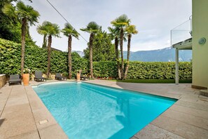 A swimming pool with palm trees and a mountain view.
