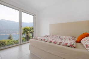 Une chambre avec un lit, une vue sur un lac et un balcon.