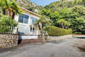 A modern house with a stone wall, a white fence, and a well-maintained garden.