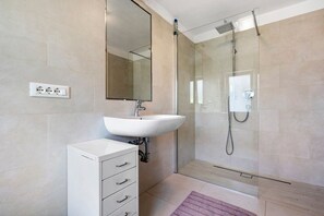 A modern bathroom with a glass-enclosed shower, a white sink, and a mirror above it. - Villa Ortensia – Exclusive Holiday Home with Pool and Panoramic Lake Garda Views (Tremosine sul Garda)