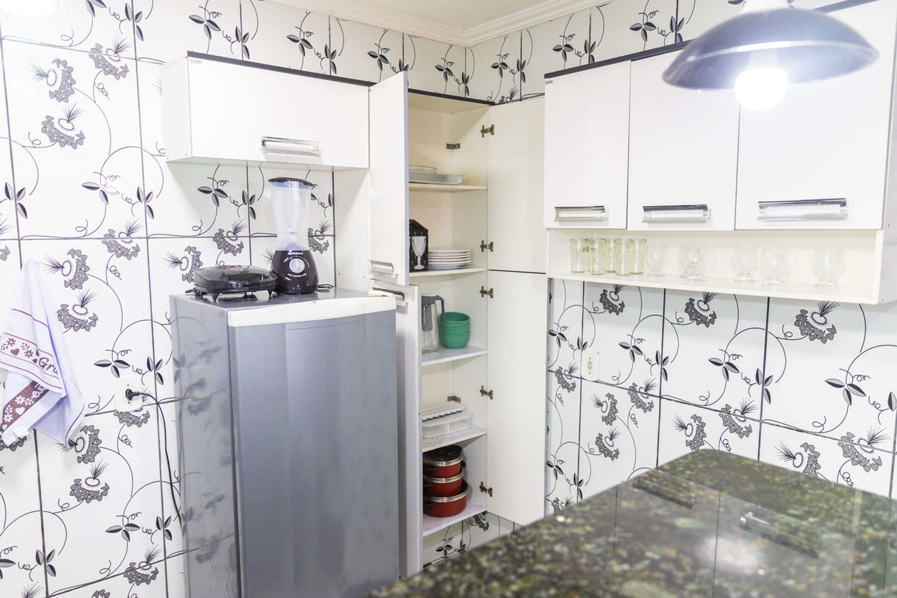 A kitchen with white cabinets, a blender on the counter, and a refrigerator.