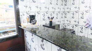Una cocina con baldosas estampadas, estufa a gas y cafetera.