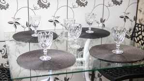 Mesa de vidrio con cuatro vasos transparentes y posavasos a juego.