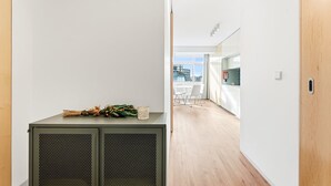 Un couloir avec un petit coin cuisine comprenant un meuble avec un récipient en verre et des légumes.