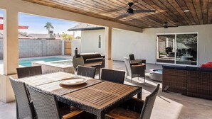 An outdoor patio with a wooden ceiling, a grill, a pool, and wicker furniture. - Desert Dream- Retreat with Heated Pool (Scottsdale)