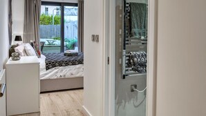 A bedroom with a bed, a bedside table, a dresser, and a sliding glass door leading to a balcony. - Plymouth City Apartment 15 (Plymouth)