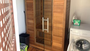 Een kamer met een houten garderobe, een glazen deur, een wasmachine en een prullenbak.