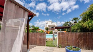 Een achtertuin met een zwembad, een pergola en een grote blauwe plantenbak.