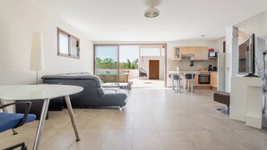 Een moderne woonkamer met een glazen tafel, een bank en uitzicht op het buiten.