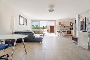 Un salon moderne avec une table en verre, un canapé et une vue sur l’extérieur.