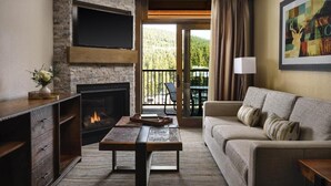 A living room with a fireplace, a sofa, a coffee table, and a TV mounted on a brick wall. - Luxury Ski-In and Ski-Out 2-Bedroom Villa at Hyatt Northstar Lodge (Truckee)