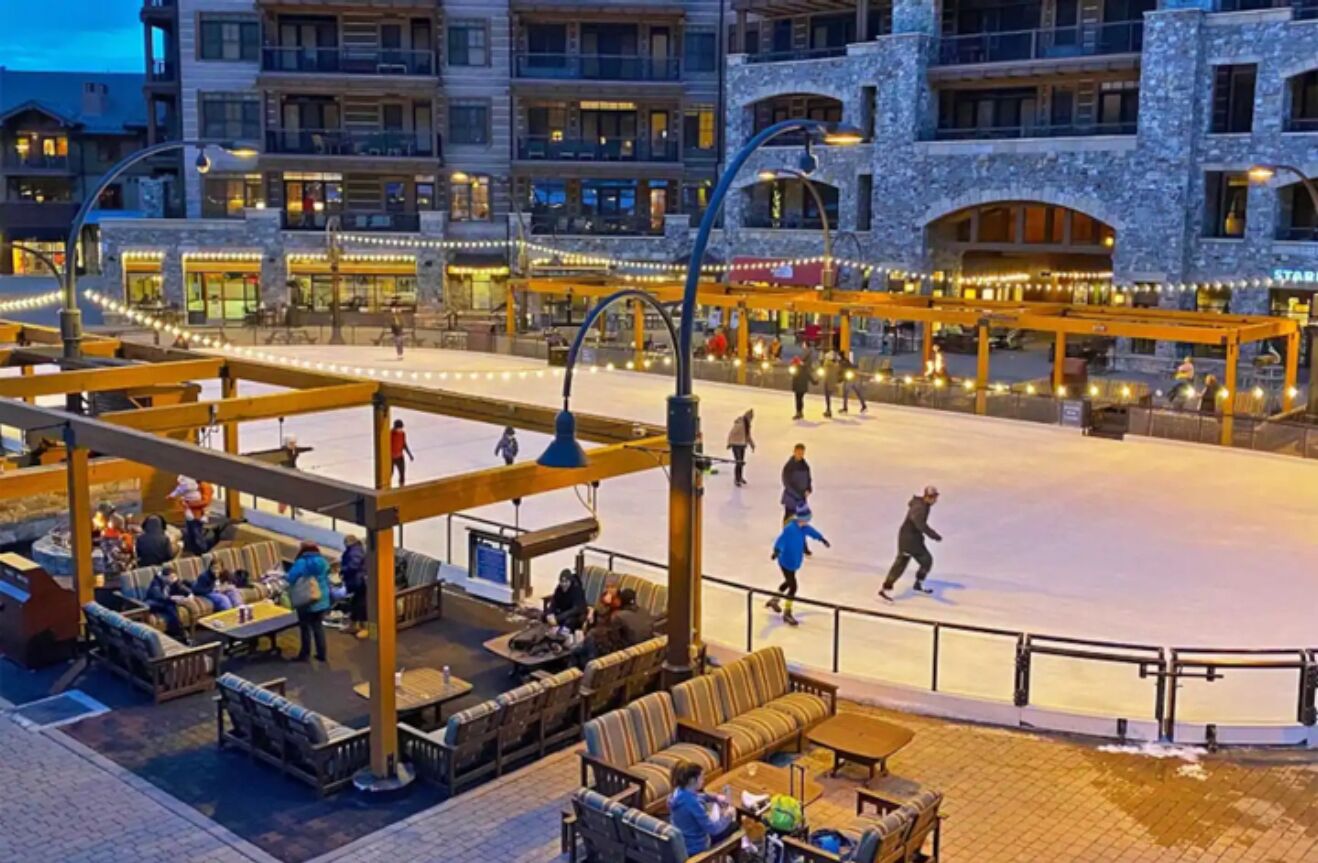 Une patinoire en plein air avec des espaces pour s’asseoir et un bâtiment en arrière-plan.