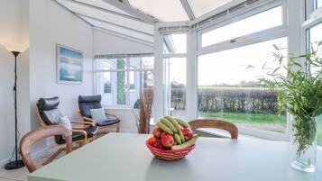 Comedor con una mesa, sillas, un frutero y vistas al exterior.