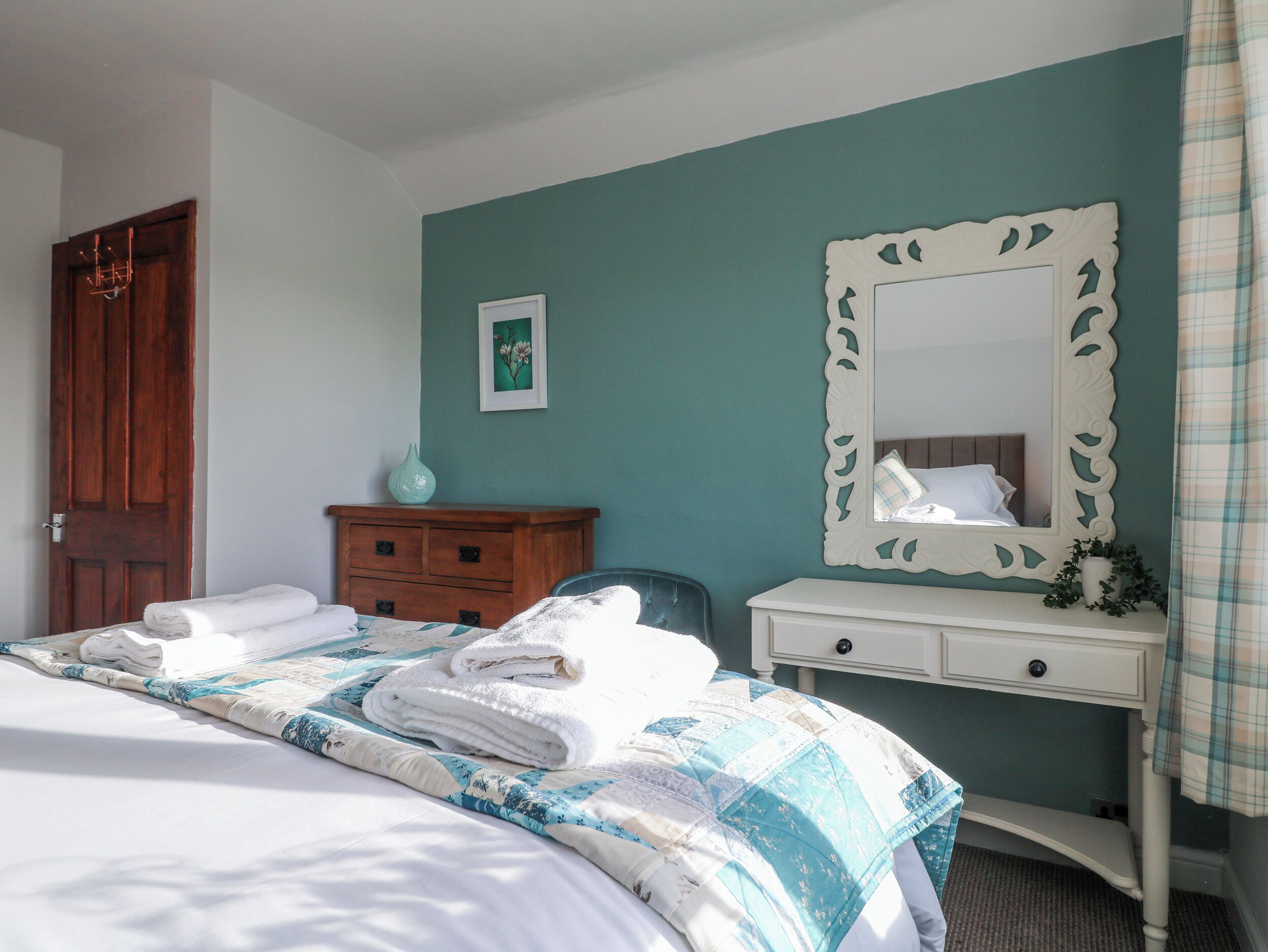 A bedroom with a bed, a dresser, a mirror, and a door.