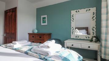 A bedroom with a bed, a dresser, a mirror, and a door.
