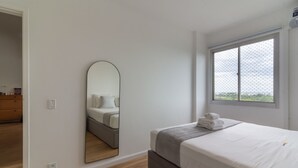 Een slaapkamer met een bed, een grote spiegel, een raam met uitzicht en een houten vloer.