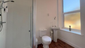 Une salle de bain avec des toilettes, un lavabo et une douche.