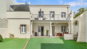A two-story building with a balcony, a covered patio, and a well-maintained lawn.